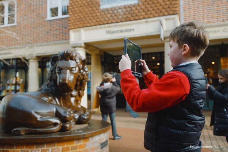 School boy photographing a lion statue using an Ipad